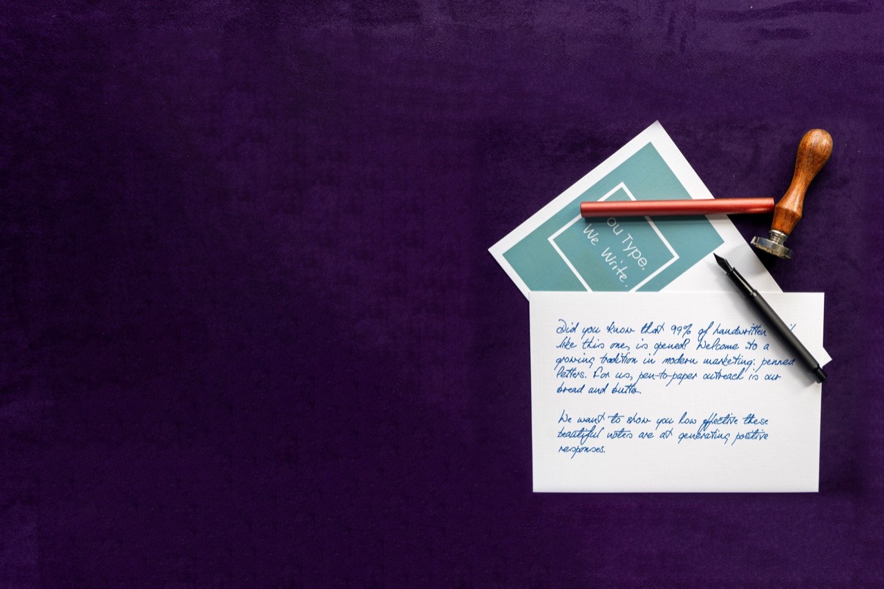 A Penned branded card and a handwritten note with a fountain pen and wax seal on purple velvet
