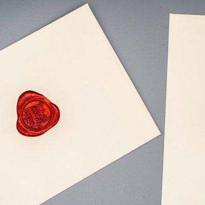A deep-red wax seal pressed onto a cream Penned envelope